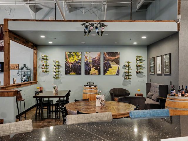 Alcove with couch, club chairs, barrels, and vineyard canvases